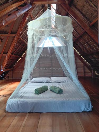 a bed with a canopy with two green pillows on it at Private villa with pool, sunset view, solar powered in Siquijor
