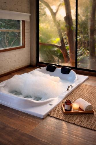 a white bath tub sitting in a room with a window at Pousada Irreplaceable in Visconde De Maua