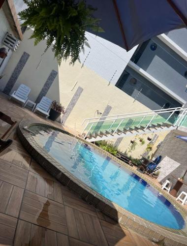 a swimming pool in a building with an umbrella at Pousada Camboinha in Cabedelo
