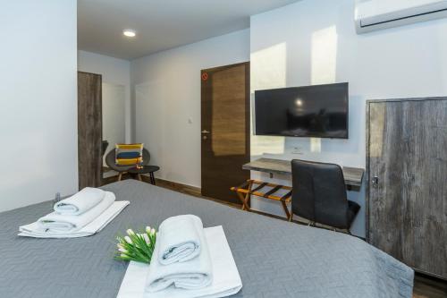 a room with a bed and a desk and a television at Apinelo Rooms in Split