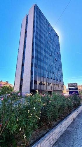 a tall glass building with flowers in front of it at Apinelo Rooms in Split
