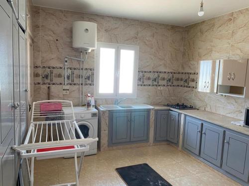 a kitchen with blue cabinets and a washing machine at Villa Joury in Al Maqārisah