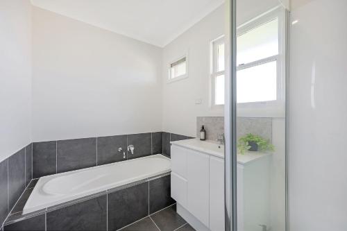 a white bathroom with a tub and a sink at Jack & Bias Cottage in Warrnambool