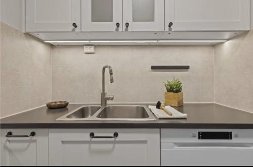 a kitchen with a sink and white cabinets at Elegant apartment in Oslo