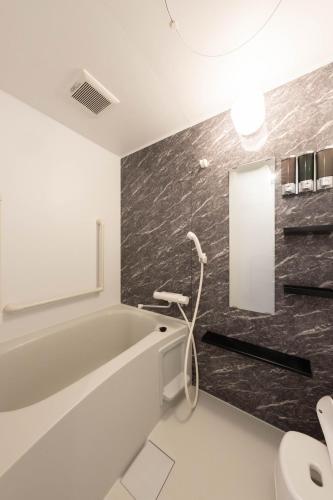 a bathroom with a bath tub and a sink at 佐藤理容Inn in Hakodate