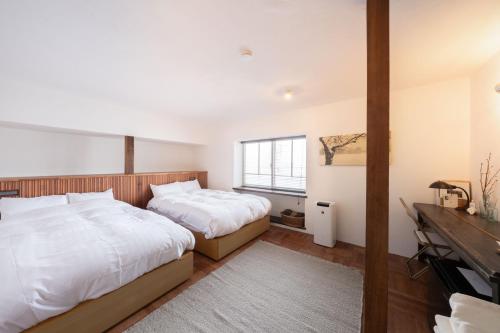 a bedroom with two beds and a desk at 佐藤理容Inn in Hakodate