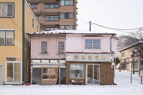 a building on a street with snow on the ground at 佐藤理容Inn in Hakodate