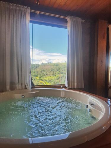 a large bath tub in a room with a window at Chalé Recanto do Pimenta 02 in Venda Nova do Imigrante
