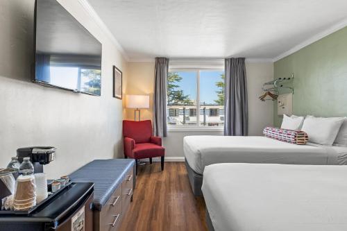 a hotel room with two beds and a red chair at Marina Village Inn in Alameda