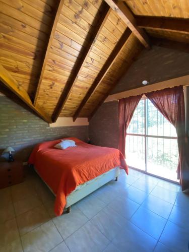 a bedroom with a red bed with a wooden ceiling at cabanas nahuel in Villa General Belgrano