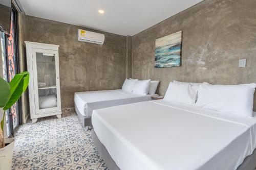 two white beds in a room with a wall at Casa Presentacion Adaz Hotel in Santa Marta