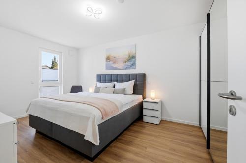 a white bedroom with a large bed and a window at Bernsteinquartier, Whg 01 03 in Kölpinsee