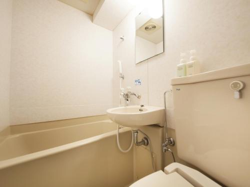 a bathroom with a sink and a toilet and a bath tub at Hotel Green Pacific in Sendai