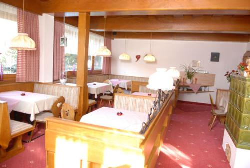 a restaurant with tables and chairs and pendant lights at Hotel-Pension Flora in Saalbach Hinterglemm