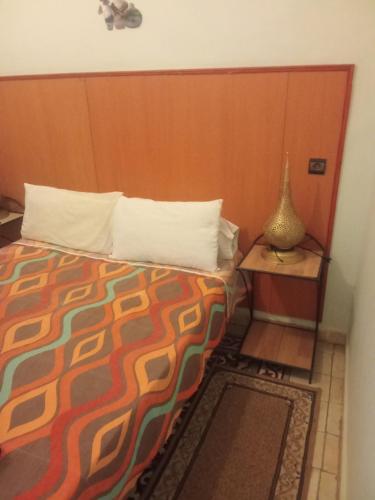 a bedroom with a bed and a table with a lamp at Hôtel des cedresazrou in Azrou