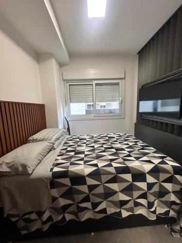 a bedroom with a black and white comforter on a bed at Loft Exclusivo - Maxplaza in Canoas