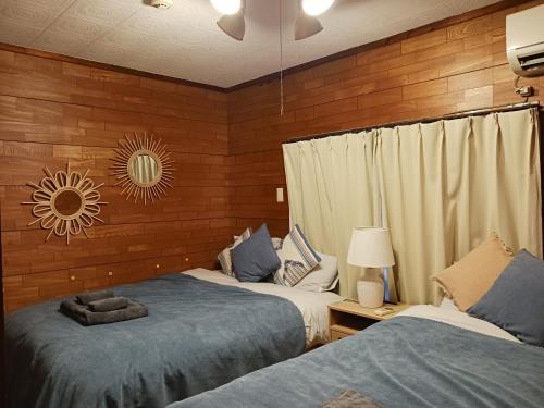 two beds in a room with wooden walls at パイナガマビーチハウス in Miyako-jima