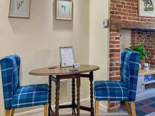 a table and two blue chairs in a waiting room at The Yeomans Cottage, Eastbridge Hospital in Canterbury