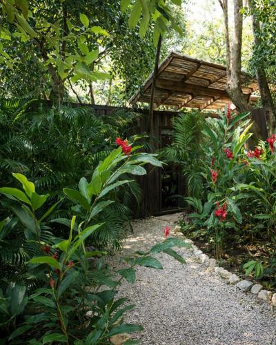 a garden with a wooden pergola and red flowers at Green Sanctuary Hotel in Nosara
