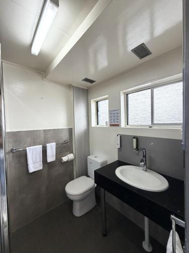a bathroom with a white toilet and a sink at Le George Motel in Port Macquarie