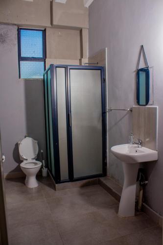 a bathroom with a shower and a toilet and a sink at The Views Apartments in Kariba