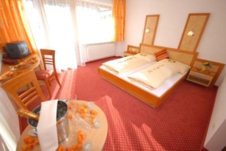 ザールバッハ・ヒンターグレムにあるHotel-Pension Floraのベッドルーム1室(ベッド2台、テーブル、テーブル・シドックスシドックス付)
