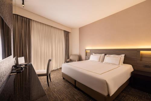 a hotel room with a large bed and a desk at Hotel Royal Queens in Singapore