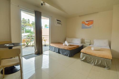 a hotel room with two beds and a balcony at ILA Apartelle Boracay in Boracay