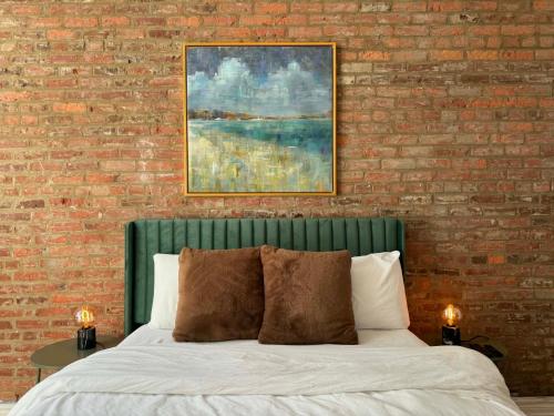 a bed with a green headboard in a bedroom with a brick wall at Top Location - The 777 Old Port Gem in Montreal