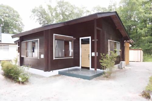 a small brown house with a door in a yard at ウッドペッカー小径 in Nasu