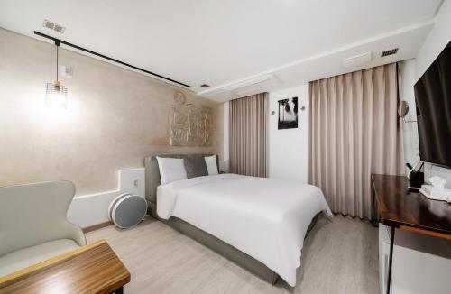a hotel room with a large white bed and a desk at Daejeon Yuseong MAC Hotel in Yusŏng