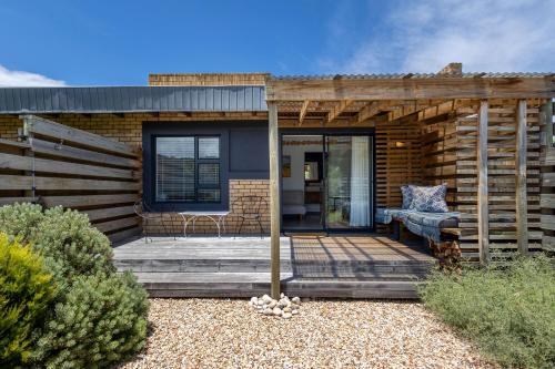 a house with a wooden deck with a couch on it at The Warren @White.Rabbit.House in Plettenberg Bay