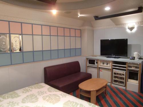 a room with a bed and a chair and a television at GOLF Kofu Showa(Adult Only) in Kofu