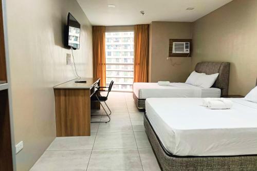 a hotel room with two beds and a desk at LTG Grand Hotel Cebu in Cebu City