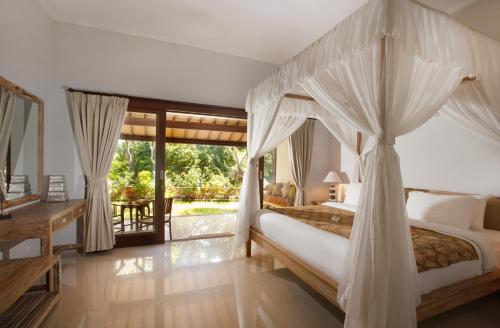 a bedroom with a canopy bed and a desk at Villa Alam Surya Ubud in Ubud