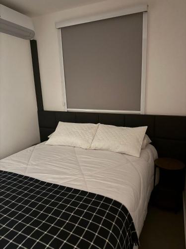 a bed in a room with a large window at Vertice House - Copacabana in Uberlândia