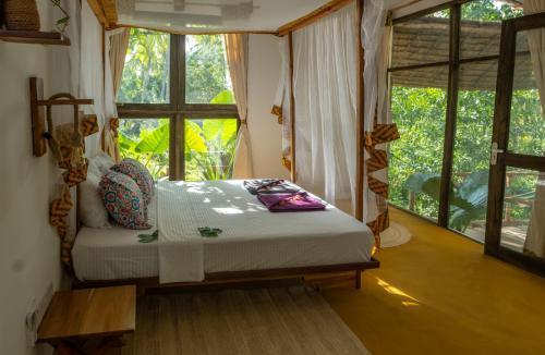 a bedroom with a bed in front of a window at LalaMafia Bungalow in Utende