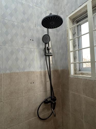 a shower with a blow dryer in a bathroom at Jassehs Apartments in Brusubi