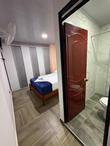 ein Schlafzimmer mit einem Bett und einer Tür, die zu einem Badezimmer führt in der Unterkunft Hotel Lancan - Pauna, Boyacá in Pauna