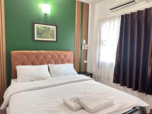 uma cama em um quarto com uma parede verde em Pakdee House em Udon Thani