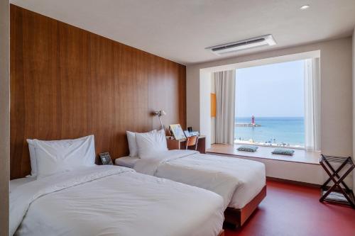 two beds in a hotel room with a large window at Cabinet 캐비넷 양양 in Yangyang