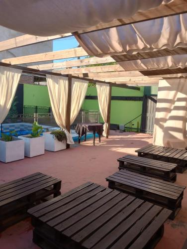 a patio with wooden benches under a white canopy at la reyna in Monte Grande