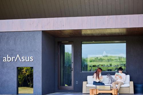 a man and a woman sitting on a couch with a dog at abrAsus house Fuji in Narusawa