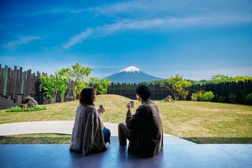 two people sitting on a table looking at a mountain at abrAsus house Fuji in Narusawa