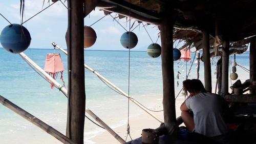 a person sitting on the beach looking at the ocean at Lanta New Beach Bungalows - SHA Plus in Ko Lanta