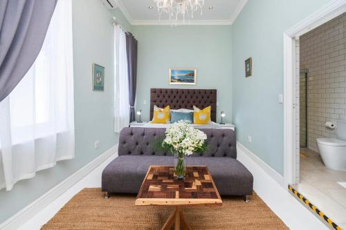 a bedroom with a couch and a table with a vase of flowers at The Willets Boutique Hotel in Simonʼs Town