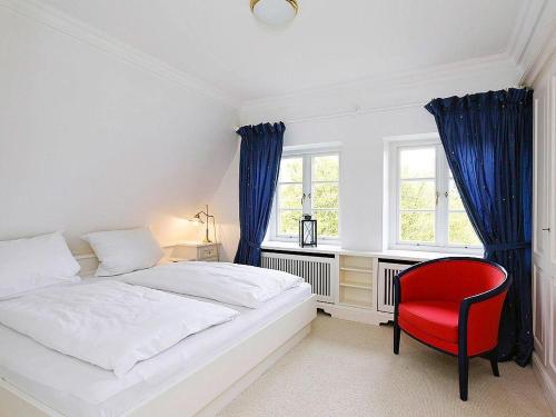 a bedroom with a bed and a red chair at Heidehaus in Kampen