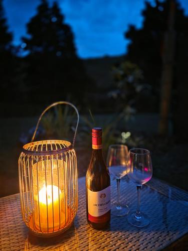 a bottle of wine and two glasses on a table at Blue Aster Retreat in Mokau