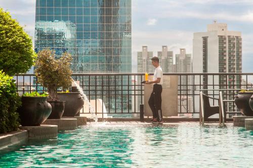 a man standing on a ledge next to a swimming pool at Banyan Tree Bangkok in Bangkok