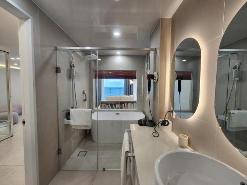 a bathroom with a tub and a sink and a mirror at Mr. Slow in Sokcho